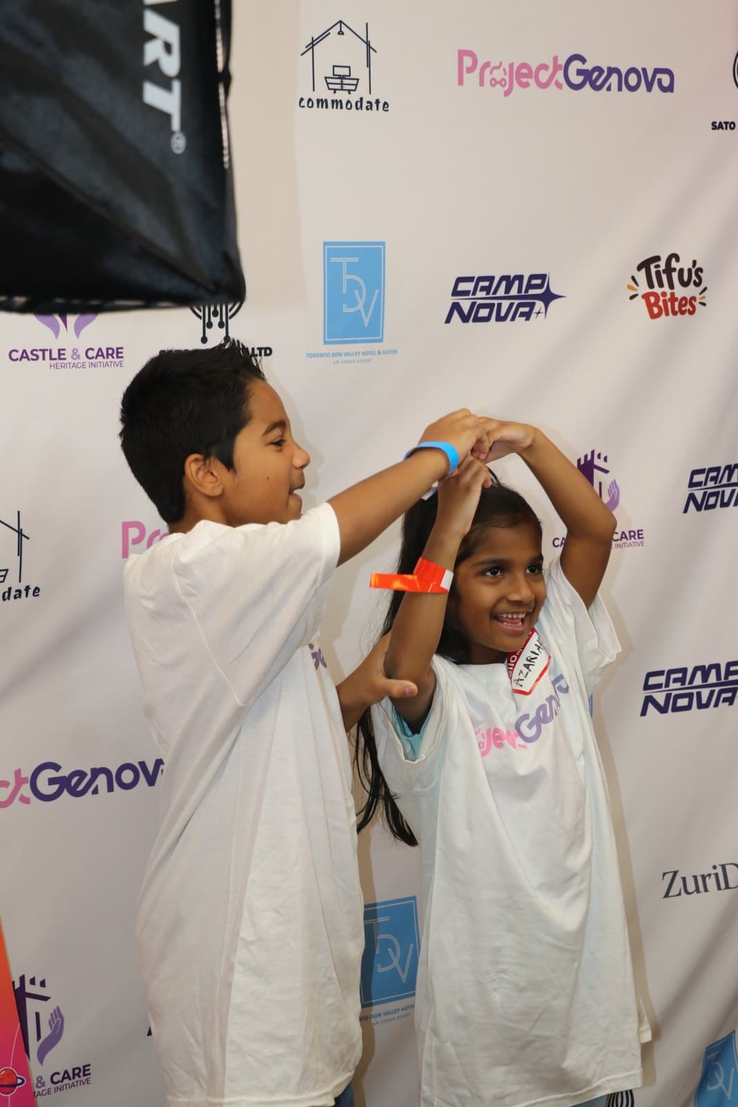 A ProjectGenova mentor guiding a young learner through code on a laptop at Camp Nova
